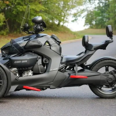 A sleek black three-wheeled motorcycle parked on a country road.