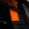 Close-up of an amber vehicle side marker light at night.