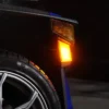 Close-up of a car's illuminated amber side marker light at night.