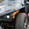 Close-up of a car's front headlight and tire with sleek design details.