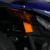 Close-up of a blue vehicle's orange indicator light and part of the wheel.