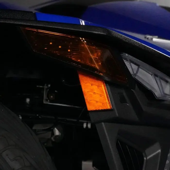 Close-up of a blue vehicle's orange indicator light and part of the wheel.