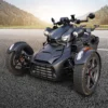 A sleek black three-wheeled motorcycle parked on a road.
