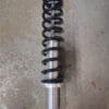 Close-up of a coil spring and shock absorber on a concrete floor.