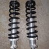 Two black and silver coilover shock absorbers on a gray surface.
