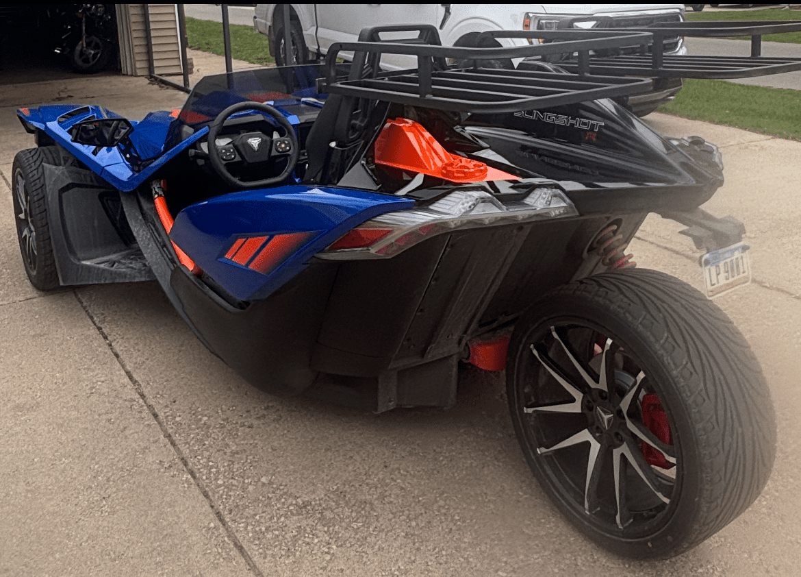 A sleek blue and orange three-wheeled motorcycle parked on a driveway.