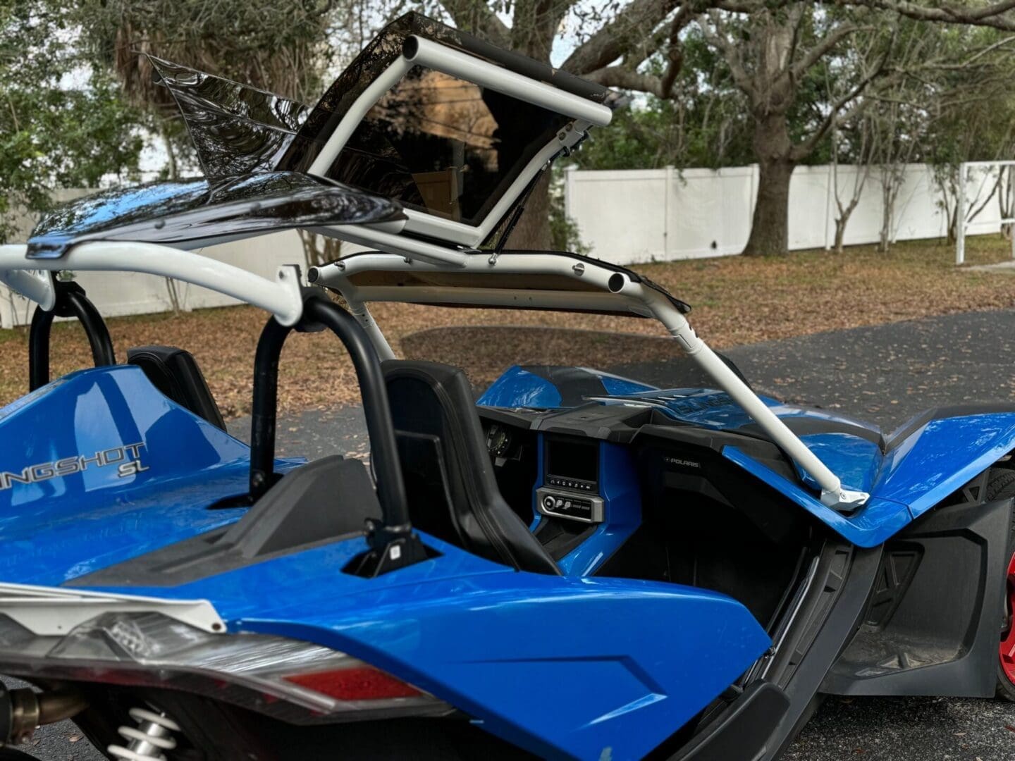 Man driving a blue dune buggy with a roll cage and open roof.